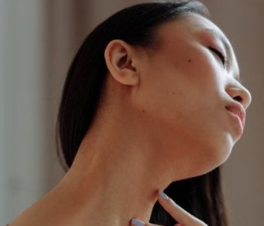 Woman touching her neck and jawline, considering double chin treatment