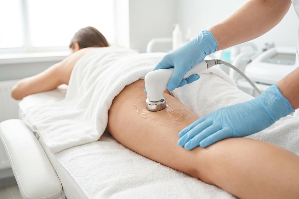 Close-up of an acoustic wave applicator gliding over the back of a woman's thigh during a zWave cellulite treatment in a San Antonio clinic